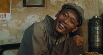 Movie still from “To Live” (1994), directed by Yimou Zhang – A man with a hat is smiling for the camera; Close Up shot, Low angle