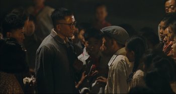 Movie still from “To Live” (1994), directed by Yimou Zhang – A group of people standing around each other in the dark; Medium shot, Over the shoulder angle
