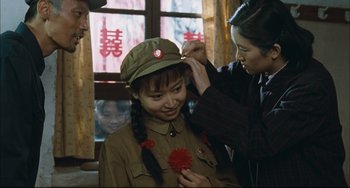 Movie still from “To Live” (1994), directed by Yimou Zhang – A woman is putting a flower in a girl's hat; Medium shot, Over the shoulder angle