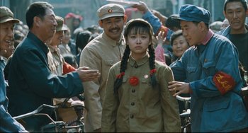 Movie still from “To Live” (1994), directed by Yimou Zhang – A young girl in a military uniform is surrounded by a crowd; Medium shot, Over the shoulder angle