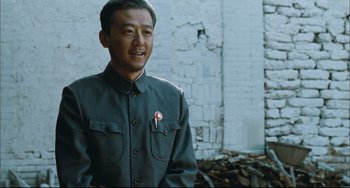 Movie still from “To Live” (1994), directed by Yimou Zhang – A man wearing a green shirt and a red pin; Medium shot, Low angle