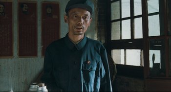 Movie still from “To Live” (1994), directed by Yimou Zhang – A man in a green shirt and a green hat; Medium shot, Low angle