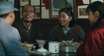 Movie still from “To Live” (1994), directed by Yimou Zhang – A man and a woman sitting at a table with food; Medium shot, Low angle