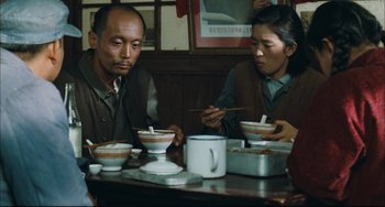 Movie still from “To Live” (1994), directed by Yimou Zhang – A man and a woman sitting at a table with bowls of food; Medium shot, Over the shoulder angle