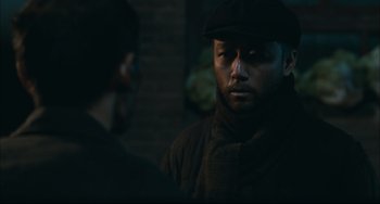 Movie still from “To Live” (1994), directed by Yimou Zhang – A man wearing a hat and a scarf is talking to another man; Close Up shot, Over the shoulder angle
