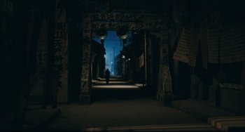 Movie still from “To Live” (1994), directed by Yimou Zhang – A person walking through a dark alley way; Extreme Wide shot, High angle