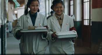 Movie still from “To Live” (1994), directed by Yimou Zhang – Two young women in lab coats holding trays of food; Medium shot, High angle