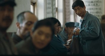 Movie still from “To Live” (1994), directed by Yimou Zhang – A group of people standing around each other in a room; Medium shot, Over the shoulder angle