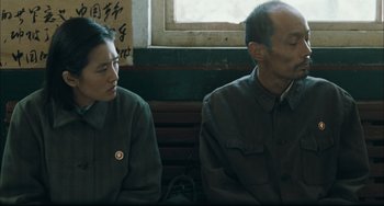 Movie still from “To Live” (1994), directed by Yimou Zhang – A man and a woman sitting next to each other on a bench; Medium shot, Over the shoulder angle