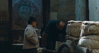 Movie still from “To Live” (1994), directed by Yimou Zhang – A man standing next to a boy next to a bicycle; Wide shot, Over the shoulder angle