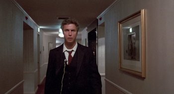 Movie still from “To Live and Die in L.A.” (1985), directed by William Friedkin – A man wearing a suit and tie in a hallway; Medium shot, Low angle