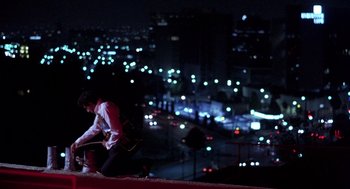 Movie still from “To Live and Die in L.A.” (1985), directed by William Friedkin – A man sitting on top of a building at night; Wide shot, High angle
