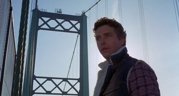 Movie still from “To Live and Die in L.A.” (1985), directed by William Friedkin – A man standing in front of a large bridge; Close Up shot, Low angle
