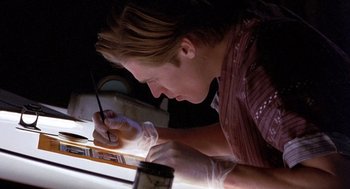 Movie still from “To Live and Die in L.A.” (1985), directed by William Friedkin – A woman is writing on a piece of paper; Close Up shot, Low angle
