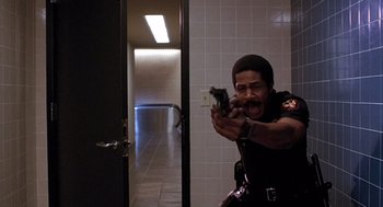 Movie still from “To Live and Die in L.A.” (1985), directed by William Friedkin – A man holding a gun in a bathroom; Medium shot, Low angle