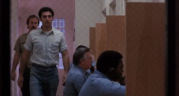 Movie still from “To Live and Die in L.A.” (1985), directed by William Friedkin – A group of people sitting in a room; Medium shot, Low angle