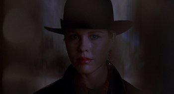 Movie still from “To Live and Die in L.A.” (1985), directed by William Friedkin – A woman wearing a black hat and a black jacket; Close Up shot, Low angle