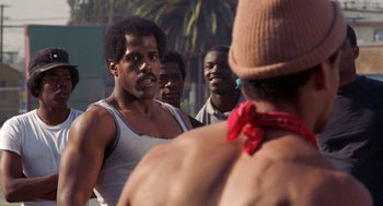 Movie still from “To Live and Die in L.A.” (1985), directed by William Friedkin – A group of men standing next to each other on the street; Close Up shot, Over the shoulder angle