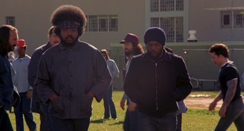 Movie still from “To Live and Die in L.A.” (1985), directed by William Friedkin – A group of men standing on top of a grass covered field; Medium shot, Low angle