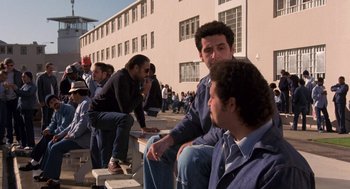 Movie still from “To Live and Die in L.A.” (1985), directed by William Friedkin – A group of men sitting next to each other on some steps; Wide shot, High angle
