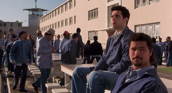 Movie still from “To Live and Die in L.A.” (1985), directed by William Friedkin – A group of people sitting on top of a bench; Medium shot, Low angle