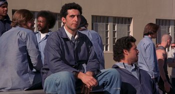 Movie still from “To Live and Die in L.A.” (1985), directed by William Friedkin – A group of men sitting next to each other on a bench; Medium shot, Low angle