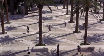 Movie still from “To Live and Die in L.A.” (1985), directed by William Friedkin – A group of people walking on a sidewalk near palm trees; Extreme Wide shot, High angle