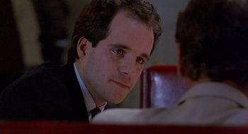 Movie still from “To Live and Die in L.A.” (1985), directed by William Friedkin – A person wearing a suit and tie; Close Up shot, Over the shoulder angle