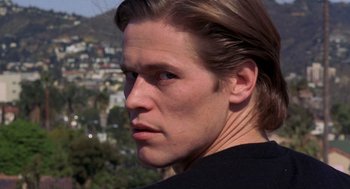 Movie still from “To Live and Die in L.A.” (1985), directed by William Friedkin – A person with long brown hair; Close Up shot, Low angle