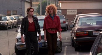 Movie still from “To Live and Die in L.A.” (1985), directed by William Friedkin – A man and a woman walking down a street; Medium shot, Low angle