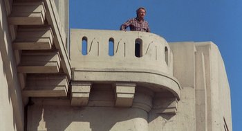 Movie still from “To Live and Die in L.A.” (1985), directed by William Friedkin – A man standing on top of a balcony; Wide shot, Low angle