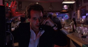 Movie still from “To Live and Die in L.A.” (1985), directed by William Friedkin – A man talking on a phone while sitting at a bar; Close Up shot, Low angle