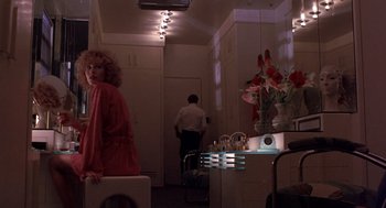 Movie still from “To Live and Die in L.A.” (1985), directed by William Friedkin – A woman standing in a room next to a man; Wide shot, Low angle
