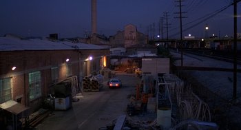 Movie still from “To Live and Die in L.A.” (1985), directed by William Friedkin – A car driving down a street at night past buildings; Extreme Wide shot, High angle