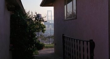 Movie still from “To Live and Die in L.A.” (1985), directed by William Friedkin – A view of a bridge from a house with a balcony; Extreme Wide shot, Low angle