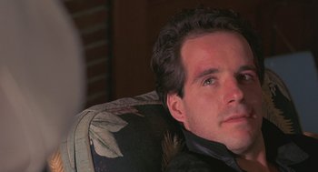 Movie still from “To Live and Die in L.A.” (1985), directed by William Friedkin – A person sitting in a chair; Close Up shot, Low angle