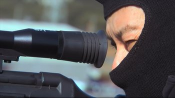 Movie still from “Tokyo Gore Police” (2008), directed by Yoshihiro Nishimura – A man looking through a telescope at something in front of him; Extreme Close Up shot, Over the shoulder angle