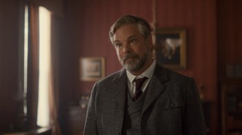 Movie still from “Anne with an E” (2017), created by Moira Walley-Beckett – An older man wearing a suit and tie in front of a painting; Close Up shot, Low angle