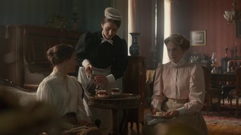 Movie still from “Anne with an E” (2017), created by Moira Walley-Beckett – A woman in a victorian era dress serving tea to two women; Medium shot, Low angle
