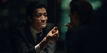 Movie still from “Tokyo Vice” (2022), created by J.T. Rogers – A man in a suit and tie holding a cigarette; Close Up shot, Over the shoulder angle