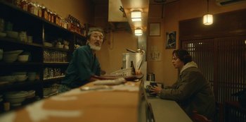 Movie still from “Tokyo Vice” (2022), created by J.T. Rogers – Two people sitting at a counter in a restaurant; Medium shot, Low angle
