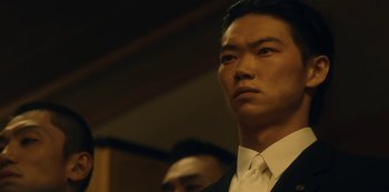 Movie still from “Tokyo Vice” (2022), created by J.T. Rogers – A person wearing a suit and tie; Close Up shot, Low angle