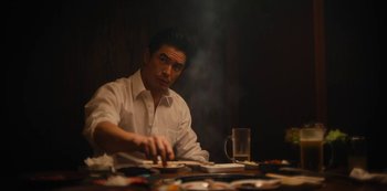 Movie still from “Tokyo Vice” (2022), created by J.T. Rogers – A man sitting at a table with a plate in front of him; Medium shot, Low angle