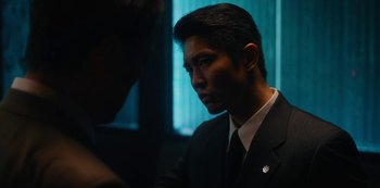 Movie still from “Tokyo Vice” (2022), created by J.T. Rogers – A man wearing a suit and tie in front of a window; Close Up shot, Over the shoulder angle
