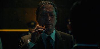 Movie still from “Tokyo Vice” (2022), created by J.T. Rogers – A man in a suit and tie smoking a cigarette; Close Up shot, Low angle