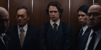 Movie still from “Tokyo Vice” (2022), created by J.T. Rogers – A man in a suit standing in front of a wooden wall; Medium shot, Low angle