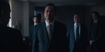 Movie still from “Tokyo Vice” (2022), created by J.T. Rogers – A man in a suit and tie standing in front of two other men; Medium shot, Low angle