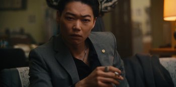 Movie still from “Tokyo Vice” (2022), created by J.T. Rogers – A person wearing a suit holding a cell phone; Close Up shot, Low angle