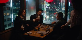 Movie still from “Tokyo Vice” (2022), created by J.T. Rogers – A group of people sitting at a table with drinks in front of a window; Medium shot, High angle