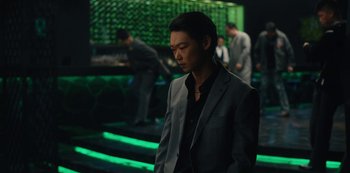 Movie still from “Tokyo Vice” (2022), created by J.T. Rogers – A man wearing a suit and tie standing in front of a bar; Medium shot, Low angle